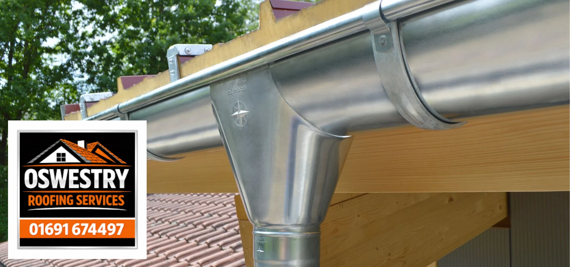 Oswestry Roofing Services Metal gutter outlet and downpipe beside a timber fascia