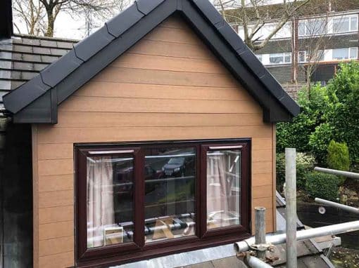 Oswestry Roofing Services Timber cladding and dark roofline trim fitted to a residential gable above a window for roofing work in Oswestry